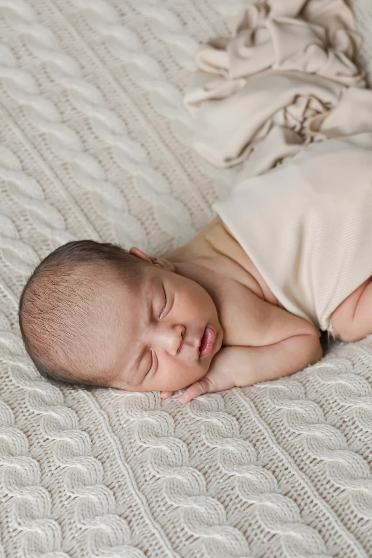 Bebê dormindo sobre uma manta de tricô clara